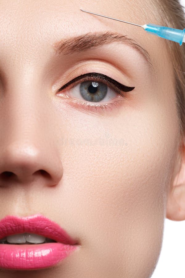 Il primo piano di bella donna ottiene l'iniezione Bello fronte e la siringa (concetto dell'iniezione del cosmetico e della chirur immagine stock libera da diritti Il primo piano di bella donna ottiene l'iniezione Bello fronte e la siringa (concetto dell'iniezione del cosmetico e della chirur immagine stock libera da diritti