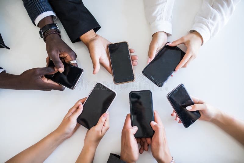 Il punto di vista dell'angolo alto delle persone di affari passa facendo uso dei telefoni cellulari Dipendenza sulle reti fotografia stock Il punto di vista dell'angolo alto delle persone di affari passa facendo uso dei telefoni cellulari Dipendenza sulle reti fotografia stock