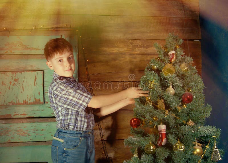 Il ragazzino felice decora l'albero di Natale immagine stock Il ragazzino felice decora l'albero di Natale immagine stock