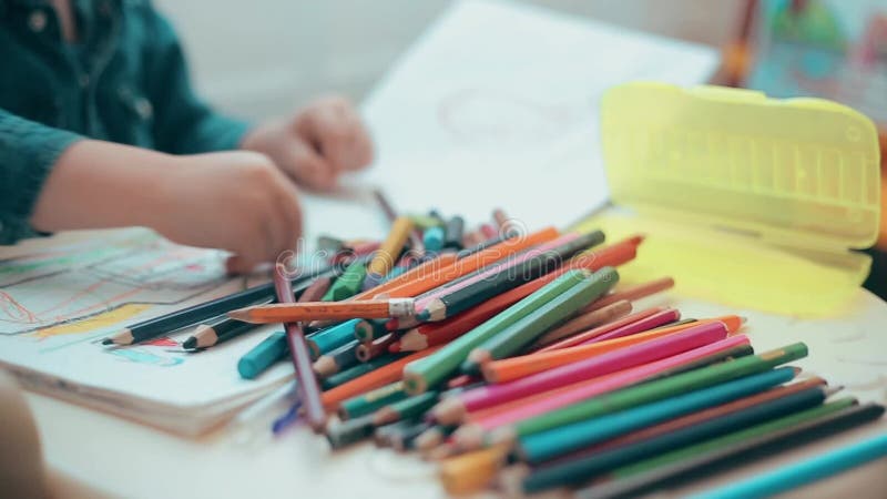 Il ragazzino impara disegnare con le matite ed i pastelli colorati