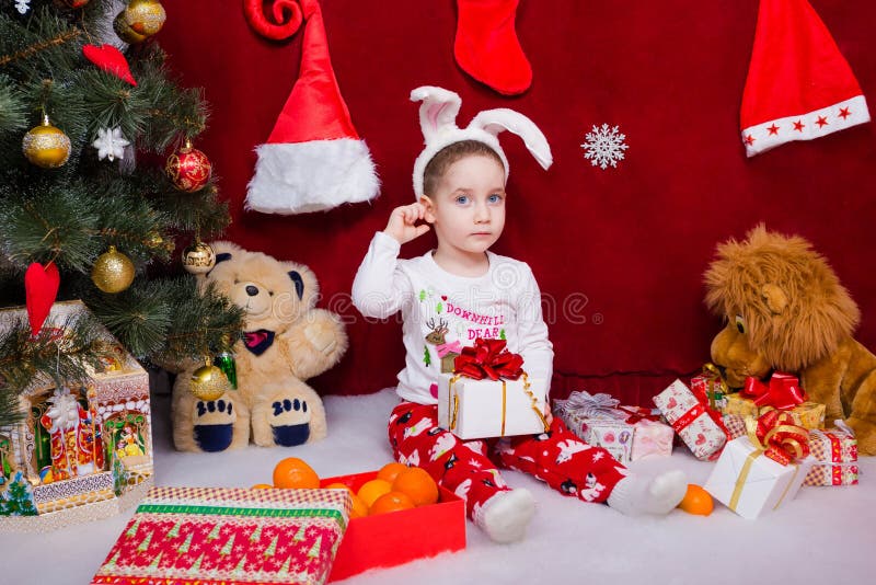 Il ragazzino sveglio sta sedendosi con un regalo di Natale fotografia stock Il ragazzino sveglio sta sedendosi con un regalo di Natale fotografia stock