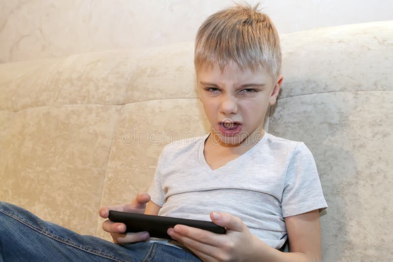 Il ragazzino è arrabbiato con i suoi genitori che prendono il telefono. concetto di dipendenza da gioco fotografie stock