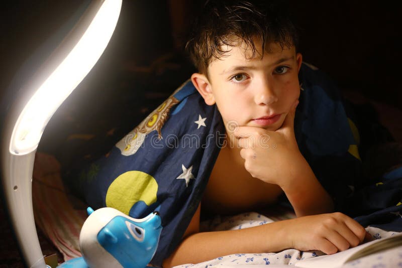 Il ragazzo bello del Preteen ha letto il libro con la lampada prima di sonno fotografie stock libere da diritti Il ragazzo bello del Preteen ha letto il libro con la lampada prima di sonno fotografie stock libere da diritti