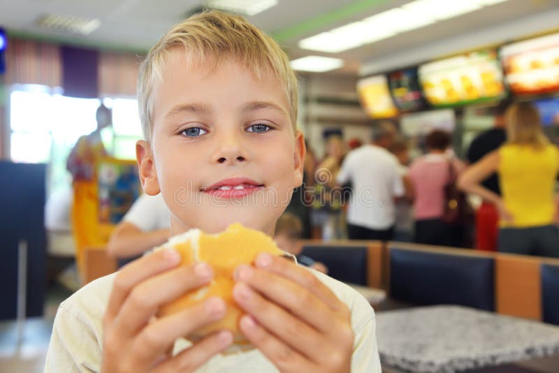 Il ragazzo mangia l'hamburger immagini stock libere da diritti Il ragazzo mangia l'hamburger immagini stock libere da diritti