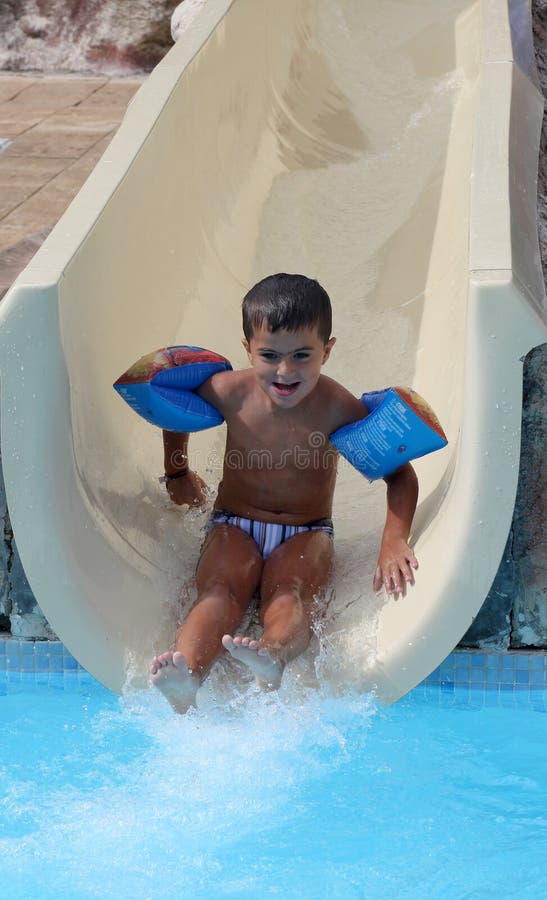 Il ragazzo sorridente fa scorrere un waterslide immagini stock Il ragazzo sorridente fa scorrere un waterslide immagini stock
