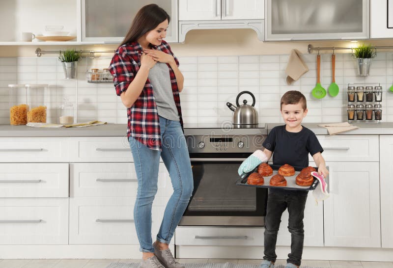 Il ragazzo sveglio che cura la madre con il forno ha cotto i panini immagini stock libere da diritti Il ragazzo sveglio che cura la madre con il forno ha cotto i panini immagini stock libere da diritti