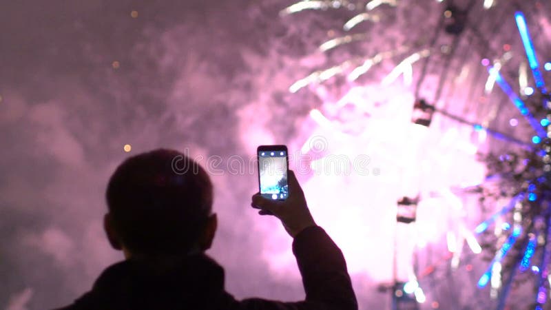 Il rallentatore della siluetta del primo piano dell'uomo che guarda e che fotografa i fuochi d'artificio esplode sulla macchina f