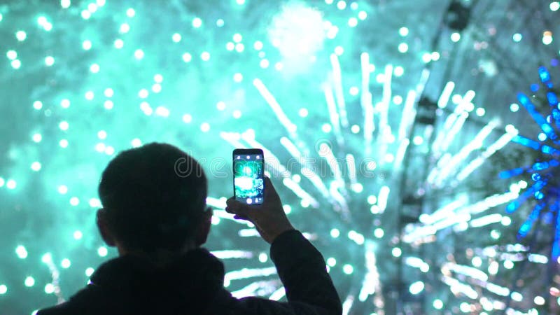 Il rallentatore della siluetta del primo piano dell'uomo che guarda e che fotografa i fuochi d'artificio esplode sulla macchina f