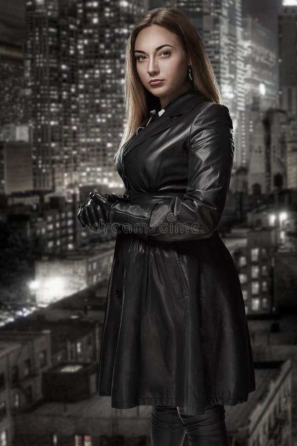 Il retro ritratto di bella donna inaccessibile in mantello nero sta contro lo sfondo della città di notte Film noir fotografie stock Il retro ritratto di bella donna inaccessibile in mantello nero sta contro lo sfondo della città di notte Film noir fotografie stock