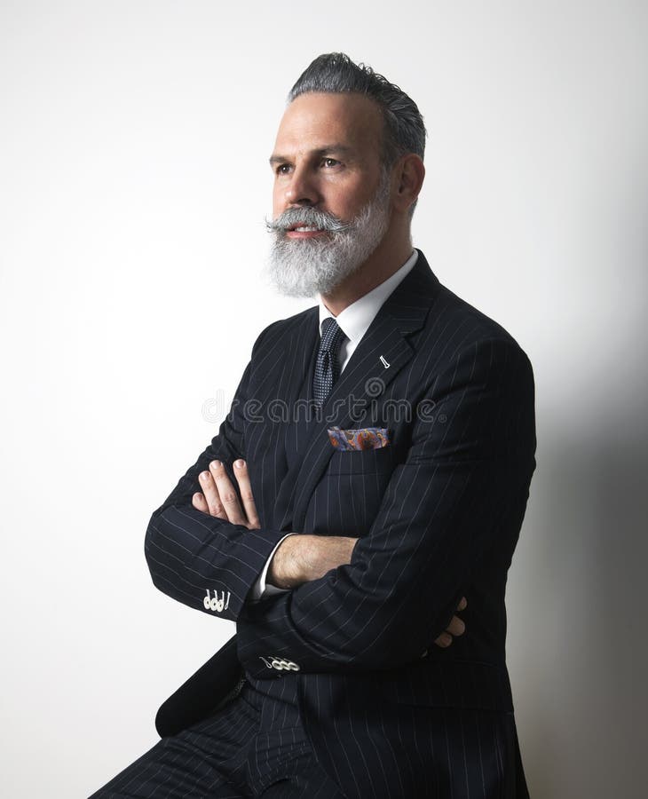 Il ritratto del mezzo barbuto attraente ha invecchiato il signore che indossa il vestito d'avanguardia sopra fondo grigio vuoto C immagine stock Il ritratto del mezzo barbuto attraente ha invecchiato il signore che indossa il vestito d'avanguardia sopra fondo grigio vuoto C immagine stock