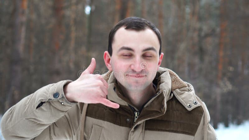 Il ritratto dell'uomo sta mostrando mi chiama gesto nella foresta dell'inverno