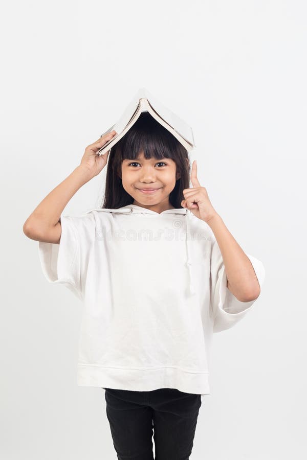 Il ritratto della bambina asiatica ha messo il libro sulla testa immagini stock libere da diritti Il ritratto della bambina asiatica ha messo il libro sulla testa immagini stock libere da diritti