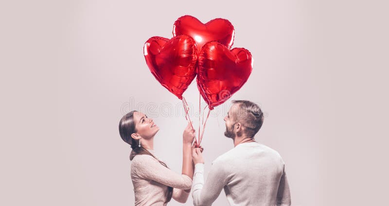 Il ritratto della ragazza sorridente di bellezza e del suo ragazzo bello che tengono il mazzo di cuore ha modellato gli aerostati fotografia stock libera da diritti Il ritratto della ragazza sorridente di bellezza e del suo ragazzo bello che tengono il mazzo di cuore ha modellato gli aerostati fotografia stock libera da diritti
