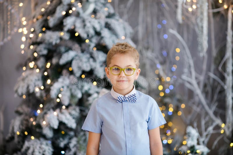 Il ritratto di Natale del ragazzo felice del bambino con lo studio dell'interno grandi di vetro, l'inverno nevoso ha decorato l'a immagine stock Il ritratto di Natale del ragazzo felice del bambino con lo studio dell'interno grandi di vetro, l'inverno nevoso ha decorato l'a immagine stock