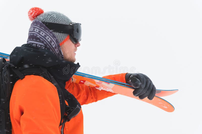 Il ritratto di uno sciatore professionista dell'atleta in un rivestimento arancio che indossa una maschera nera e con gli sci sul immagine stock Il ritratto di uno sciatore professionista dell'atleta in un rivestimento arancio che indossa una maschera nera e con gli sci sul immagine stock