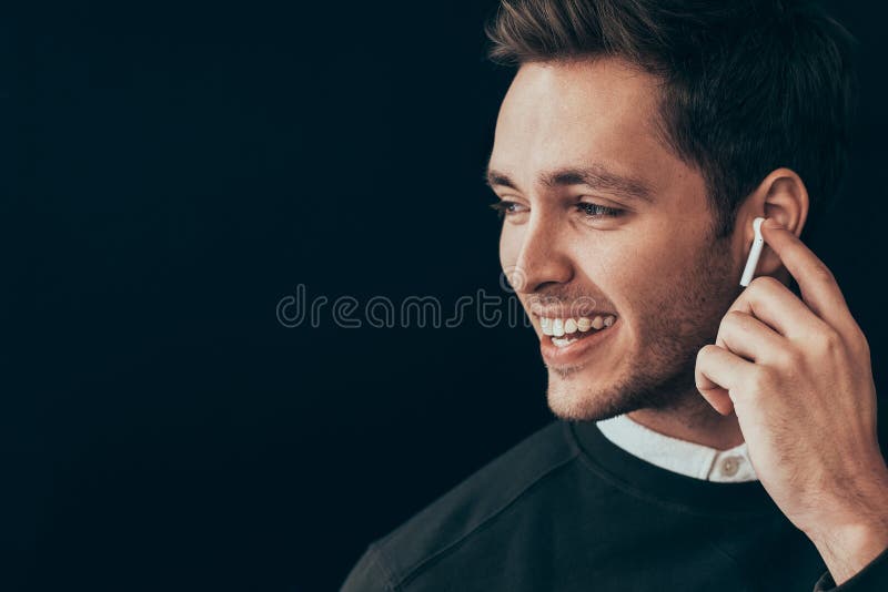 Il ritratto orizzontale del primo piano di giovane uomo bello che sorride ed ha una chiamata con un collega isolato su fondo nero immagini stock Il ritratto orizzontale del primo piano di giovane uomo bello che sorride ed ha una chiamata con un collega isolato su fondo nero immagini stock