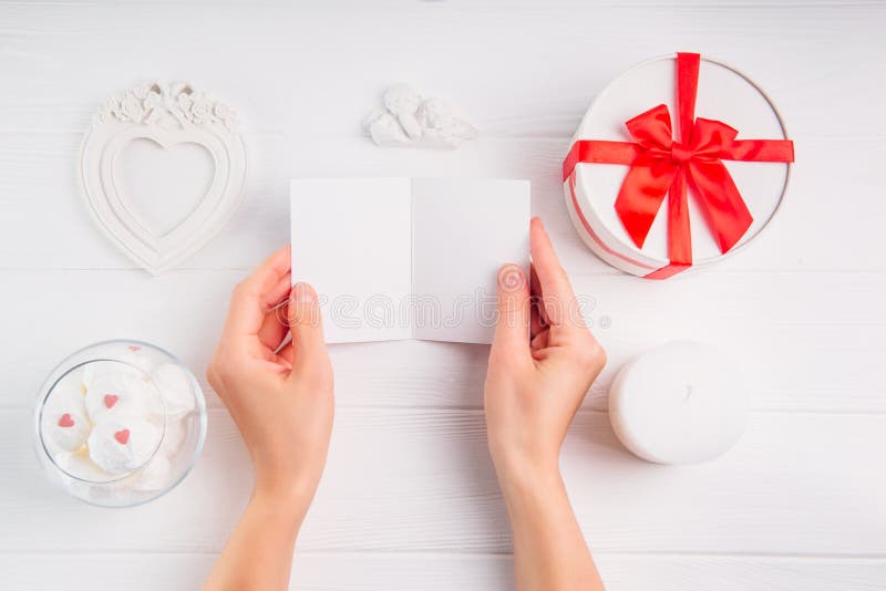 Il ` s delle donne passa la tenuta della cartolina d'auguri vuota su fondo bianco con la decorazione romantica come giftbox, stru fotografia stock libera da diritti Il ` s delle donne passa la tenuta della cartolina d'auguri vuota su fondo bianco con la decorazione romantica come giftbox, stru fotografia stock libera da diritti