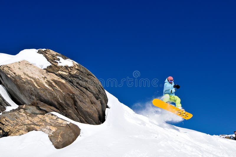 Il salto dello Snowboarder della scogliera alla neve fresca immagine stock Il salto dello Snowboarder della scogliera alla neve fresca immagine stock