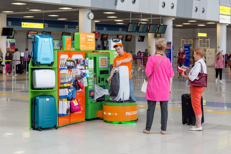 Il servo imballa i bagagli dei passeggeri prima di imbarcarsi su un aereo Vista interna dell'aeroporto internazionale di Vladivos immagini stock Il servo imballa i bagagli dei passeggeri prima di imbarcarsi su un aereo Vista interna dell'aeroporto internazionale di Vladivos immagini stock