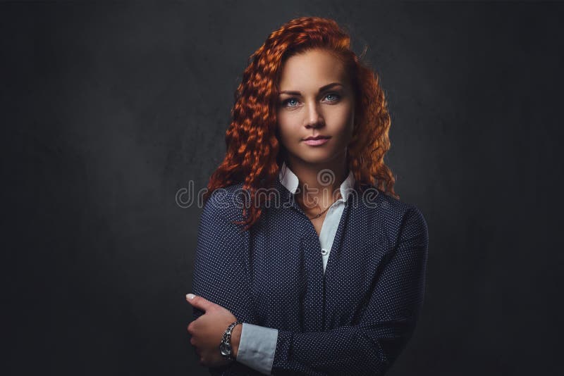 Il supervisore femminile della testarossa si è vestito in un vestito elegante sopra fondo grigio