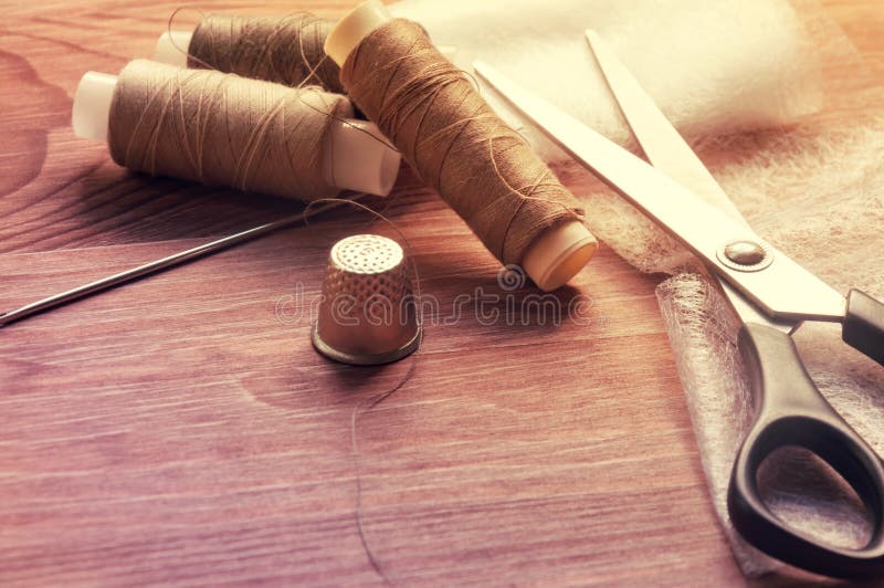 Il tailor& x27; scrittorio di s Vecchi tamburi o matasse di legno di cucito su un vecchio worktable di legno con le forbici Tonif