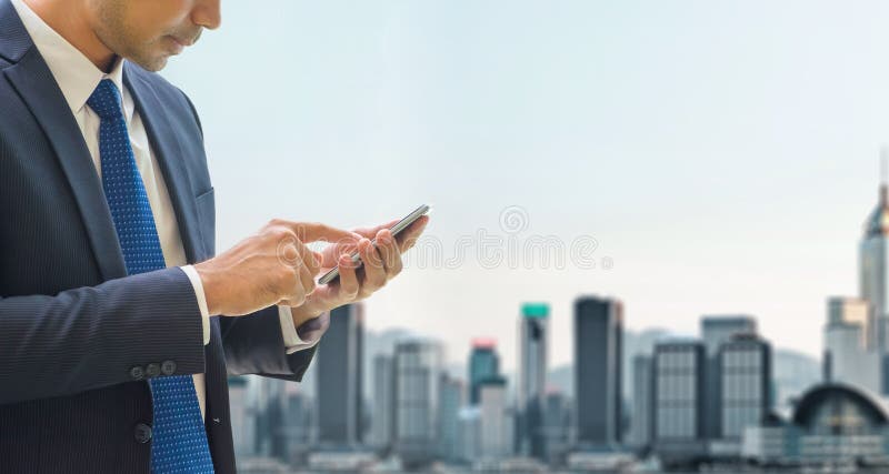 Il telefono cellulare di uso dell'uomo di affari in cima all'edificio per uffici vede la vista immagini stock Il telefono cellulare di uso dell'uomo di affari in cima all'edificio per uffici vede la vista immagini stock