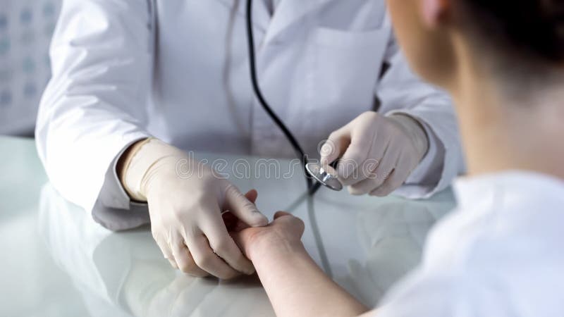 Il terapista che controlla le femmine pulsa con lo stetoscopio, appuntamento alla clinica, salute fotografia stock Il terapista che controlla le femmine pulsa con lo stetoscopio, appuntamento alla clinica, salute fotografia stock