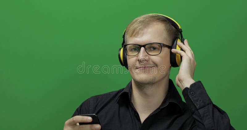 Il tipo ascolta musica in cuffie gialle senza fili Schermo verde fotografia stock Il tipo ascolta musica in cuffie gialle senza fili Schermo verde fotografia stock
