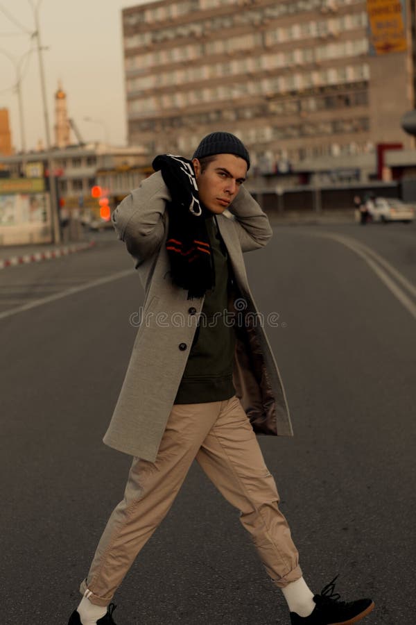 Il tipo bello in vestiti alla moda cammina su una via della città al tramonto fotografie stock libere da diritti