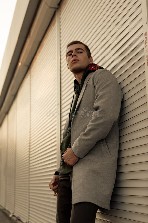 Il tipo bello in vestiti alla moda cammina su una via della città al tramonto immagine stock