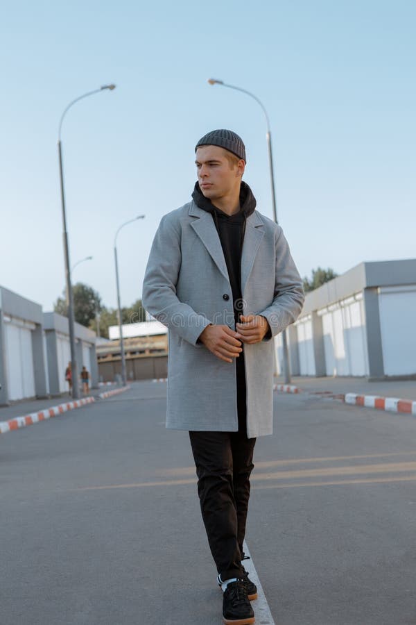Il tipo bello in vestiti alla moda cammina su una via della città al tramonto immagine stock libera da diritti
