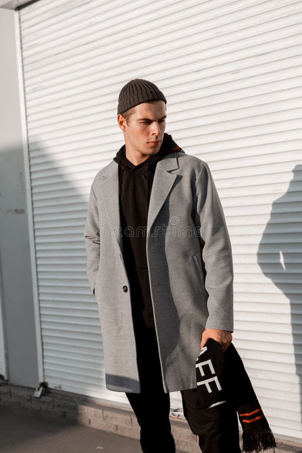 Il tipo bello in vestiti alla moda cammina su una via della città al tramonto fotografia stock libera da diritti