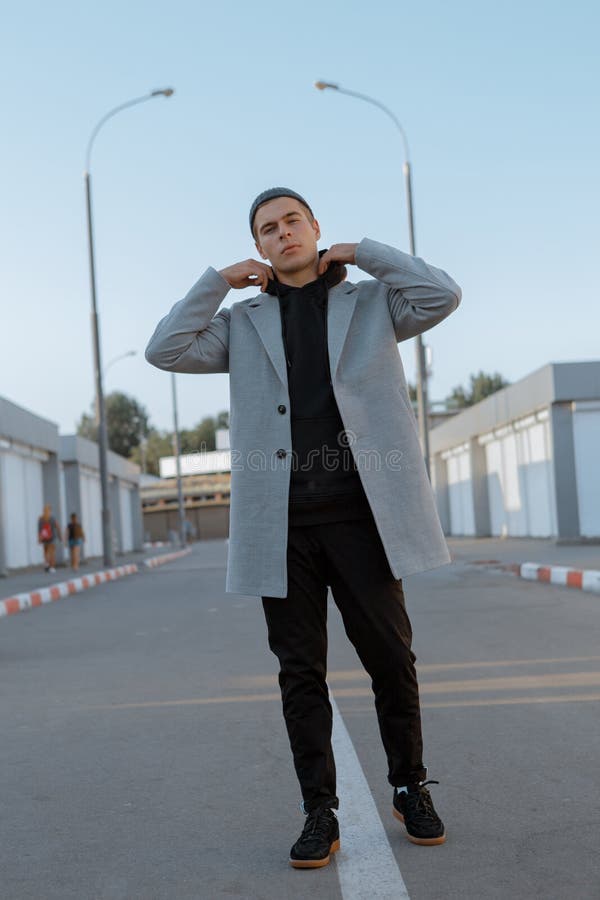 Il tipo bello in vestiti alla moda cammina su una via della città al tramonto immagini stock libere da diritti