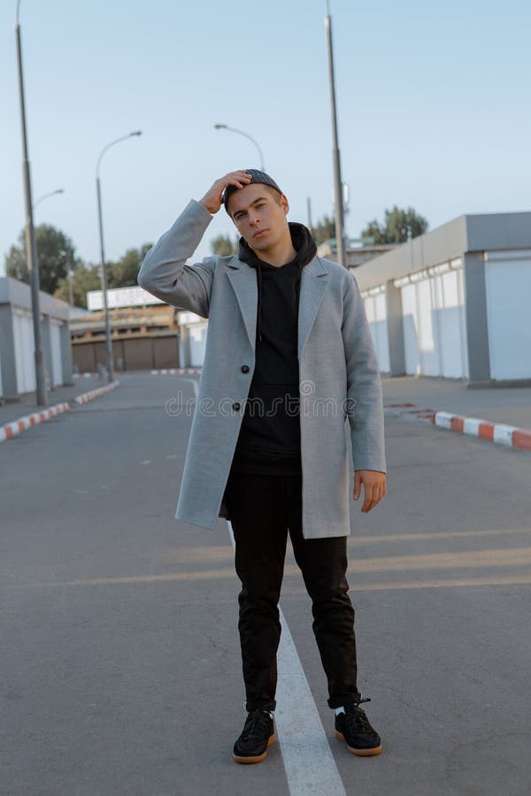 Il tipo bello in vestiti alla moda cammina su una via della città al tramonto fotografia stock