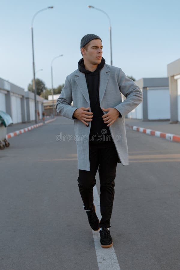 Il tipo bello in vestiti alla moda cammina su una via della città al tramonto immagine stock