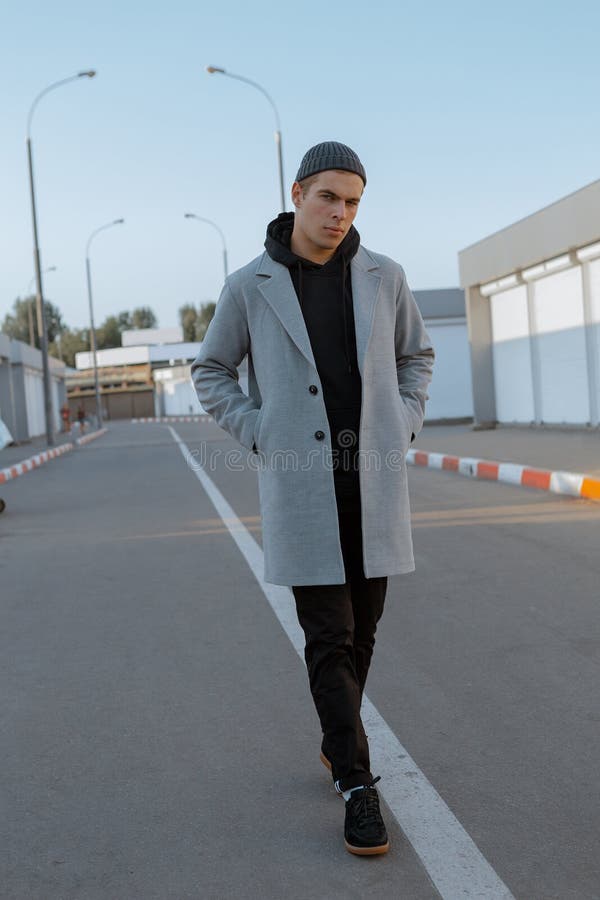 Il tipo bello in vestiti alla moda cammina su una via della città al tramonto fotografia stock