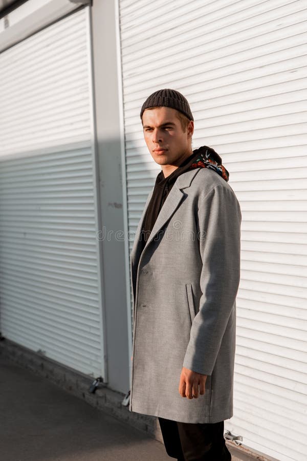 Il tipo bello in vestiti alla moda cammina su una via della città al tramonto fotografia stock
