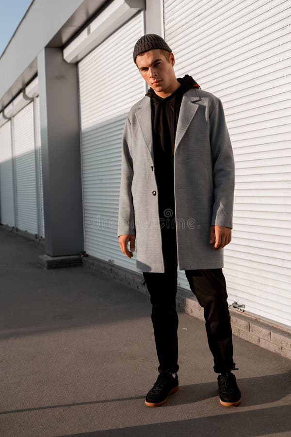 Il tipo bello in vestiti alla moda cammina su una via della città al tramonto fotografia stock