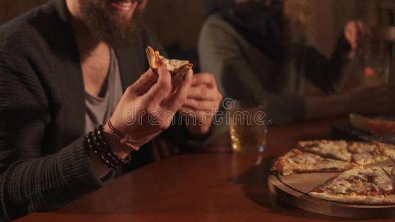 Il tipo sta prendendo la pizza dal piatto in un ristorante durante la cena con i colleghi