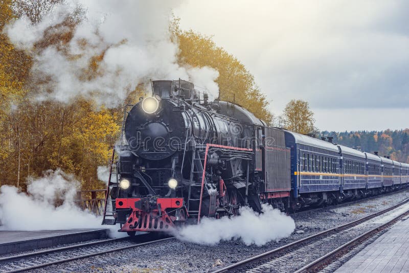 Il treno a vapore retrò arriva alla stazione di servizio su una piattaforma di legno. ruskeala fotografia stock libera da diritti