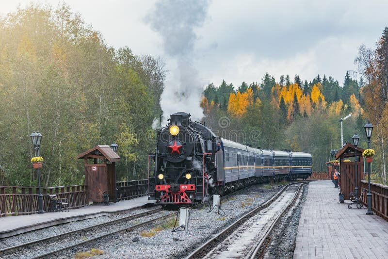 Il treno a vapore retrò arriva alla stazione a marciapiede di legno nella nuvolosa serata autunnale fotografie stock libere da diritti