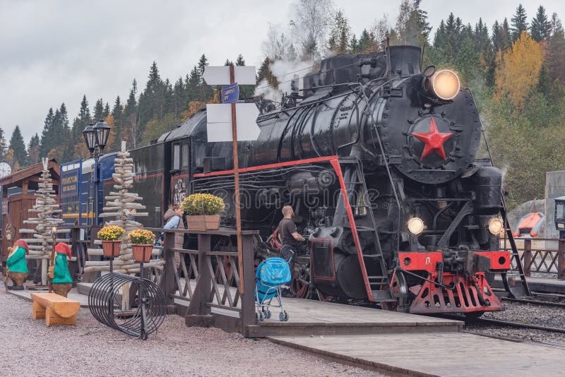 Il treno a vapore retrò arriva alla stazione su una piattaforma di legno da sortavala nella nuvolosa serata d'autunno fotografie stock