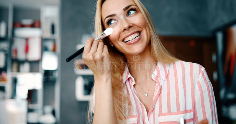 Il truccatore che applica il fondamento tonale liquido sul fronte della donna compone la stanza immagine stock libera da diritti Il truccatore che applica il fondamento tonale liquido sul fronte della donna compone la stanza immagine stock libera da diritti