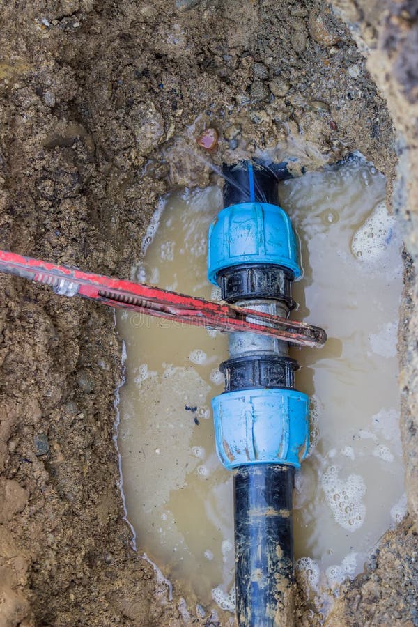 Il tubo rotto del PVC in fossa con la chiave cola l'acqua 2 immagini stock libere da diritti Il tubo rotto del PVC in fossa con la chiave cola l'acqua 2 immagini stock libere da diritti