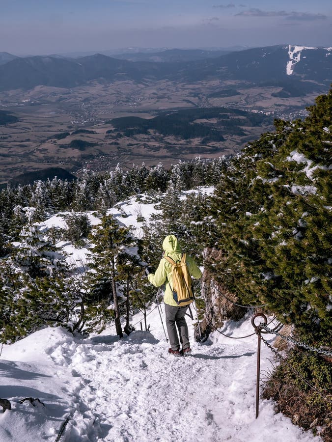 Il turista discende lungo un percorso ripido e innevato fissato dalle catene, stupenti le viste nel fondo, orario invernale immagine stock Il turista discende lungo un percorso ripido e innevato fissato dalle catene, stupenti le viste nel fondo, orario invernale immagine stock