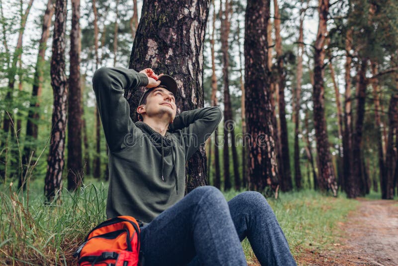Il turista stanco dell'uomo che dorme nel viaggiatore della foresta di primavera ha smesso di avere resto che si accampa, concett immagine stock Il turista stanco dell'uomo che dorme nel viaggiatore della foresta di primavera ha smesso di avere resto che si accampa, concett immagine stock