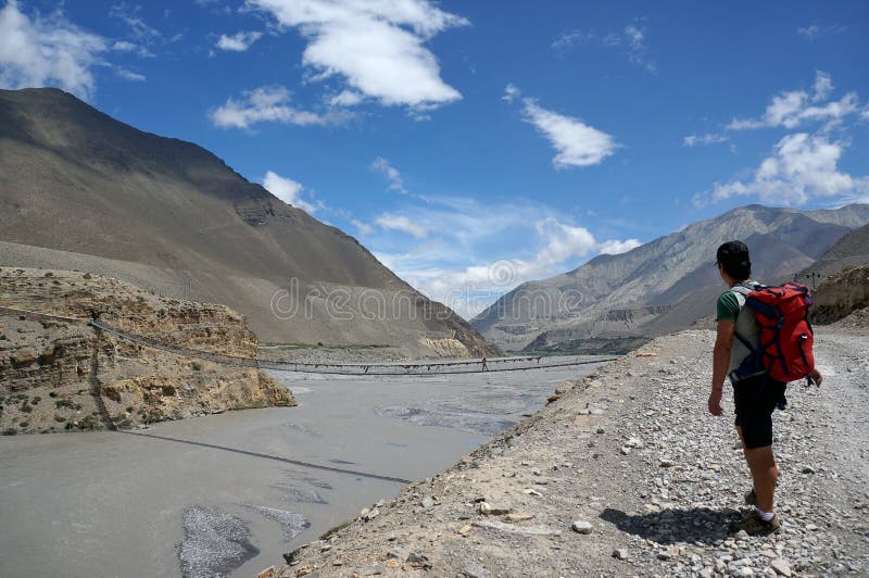 Il turista è stante ed esaminante il ponte sospeso attraverso Kali Gandaki River immagini stock libere da diritti Il turista è stante ed esaminante il ponte sospeso attraverso Kali Gandaki River immagini stock libere da diritti