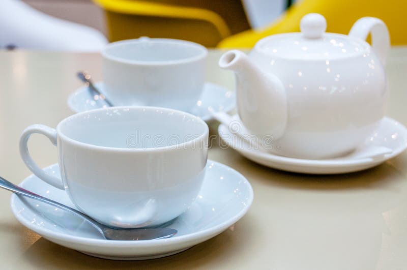 Il tè ceramico bianco due aggredisce con i cucchiai ed i piattini brillanti fotografia stock Il tè ceramico bianco due aggredisce con i cucchiai ed i piattini brillanti fotografia stock