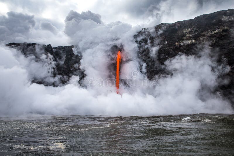 Il vapore scoppia dall'oceano freddo mentre la lava calda versa nell'acqua fotografie stock Il vapore scoppia dall'oceano freddo mentre la lava calda versa nell'acqua fotografie stock