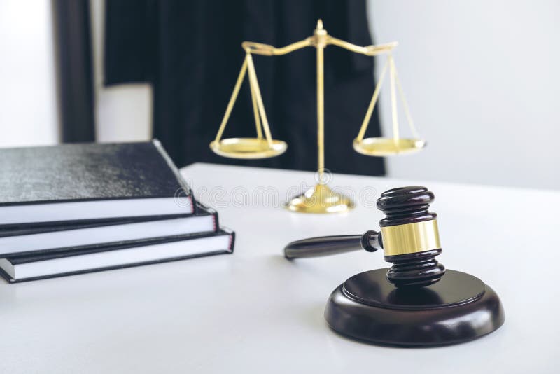 Il vestito dell'avvocato, libri di legge, un martelletto e bilancia della giustizia su w fotografia stock Il vestito dell'avvocato, libri di legge, un martelletto e bilancia della giustizia su w fotografia stock